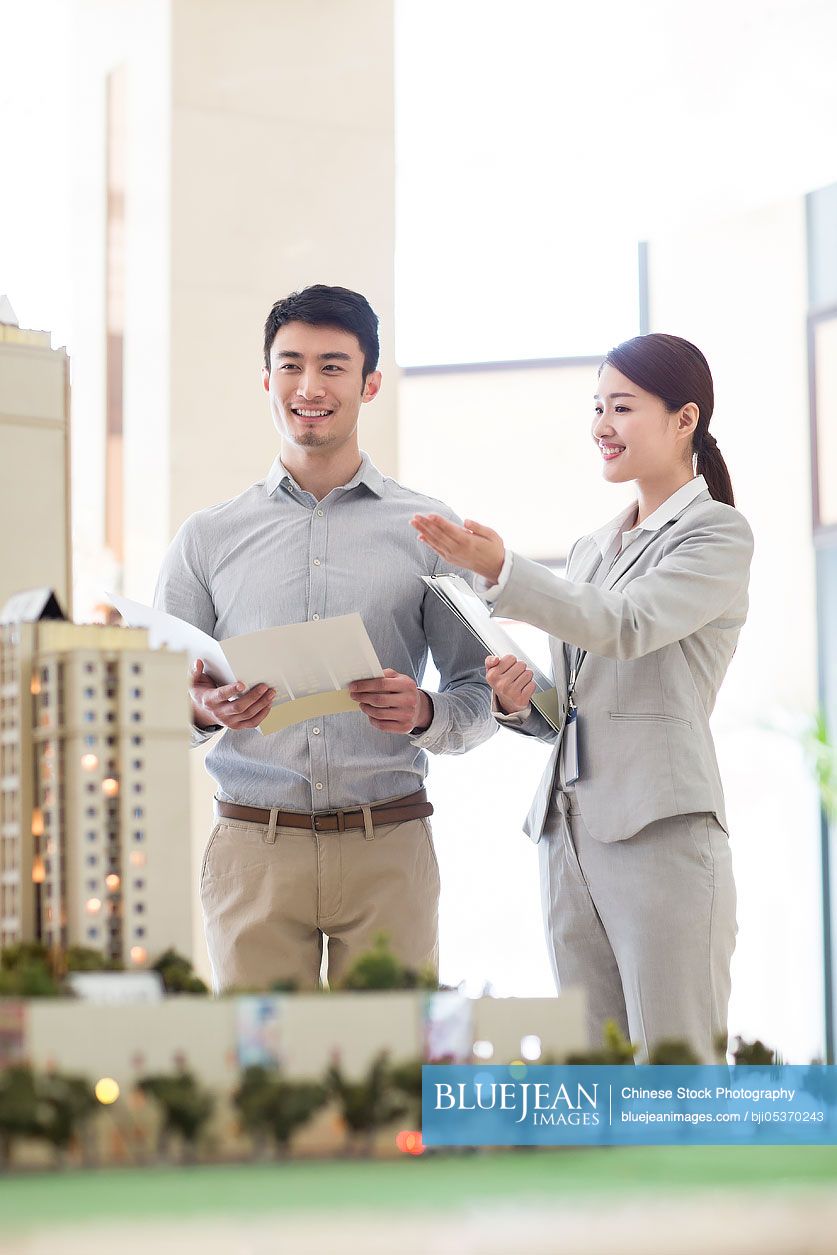 Chinese realtor showing architectural model to young manHighres stock