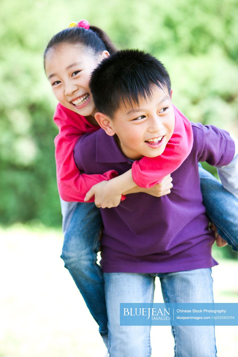 Young girl carrying sister giving piggyback ride Stock Photo