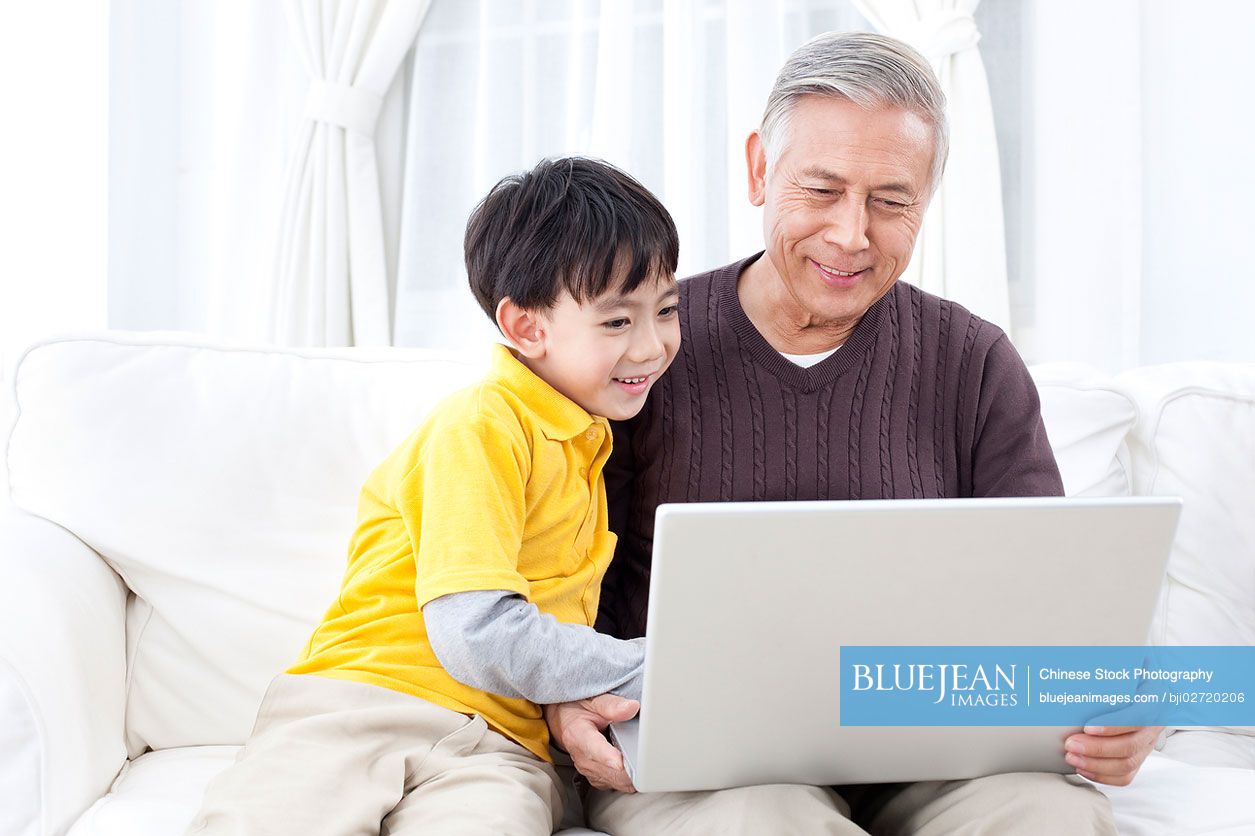 Chinese grandpa and grandson using laptop