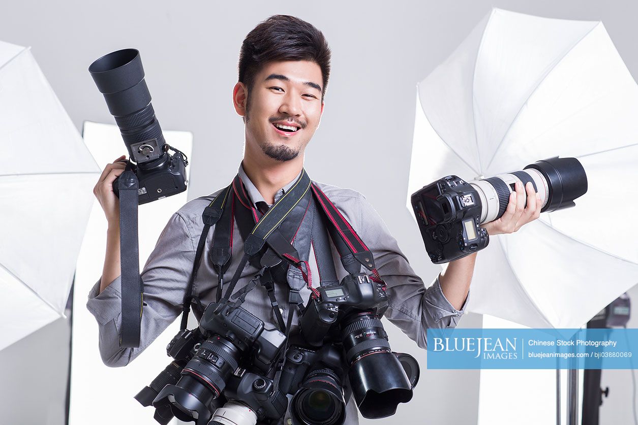 Portrait of Chinese photographer with many cameras hanging on his neck