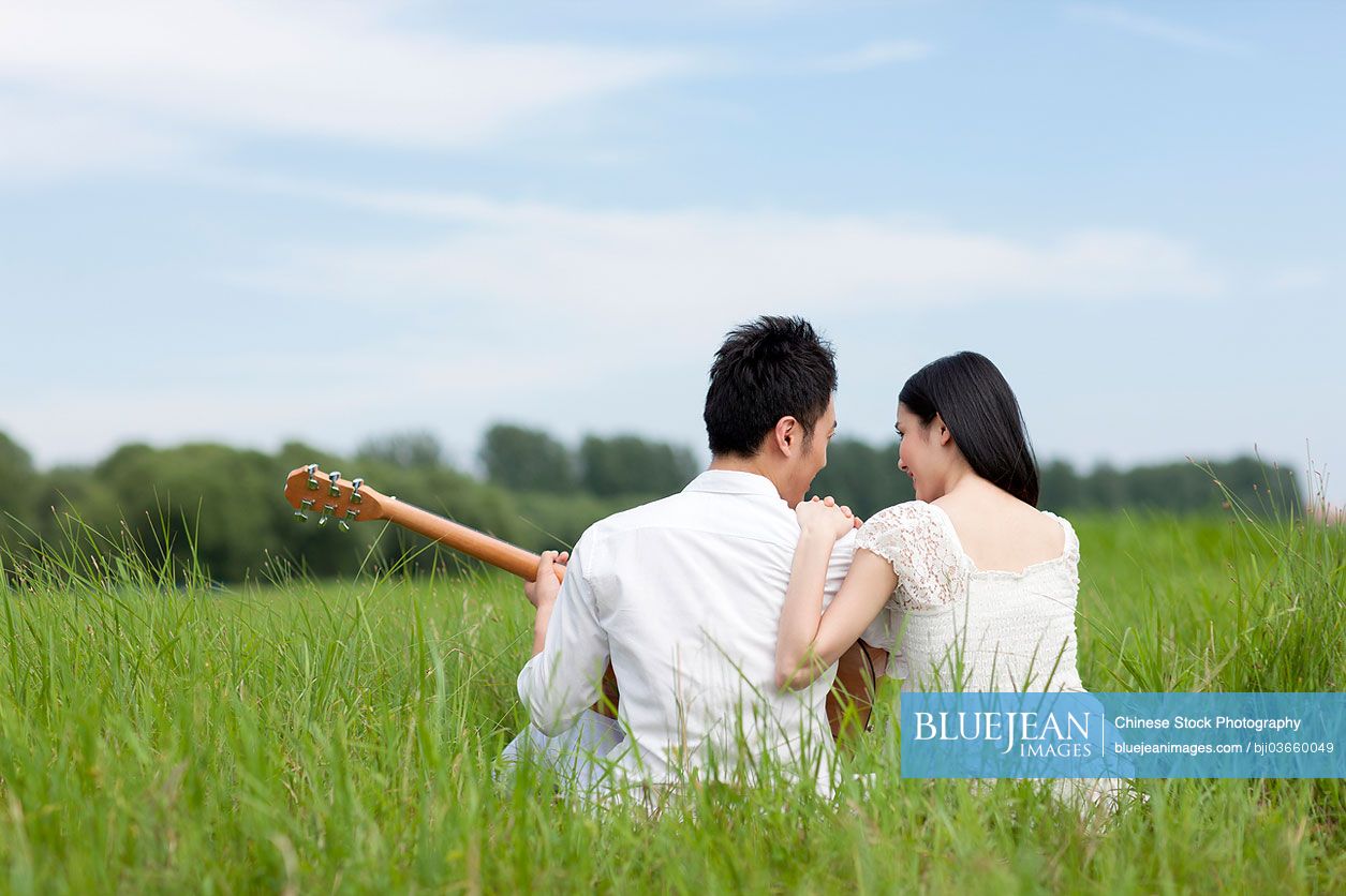 Young Chinese couple enjoying music outdoors