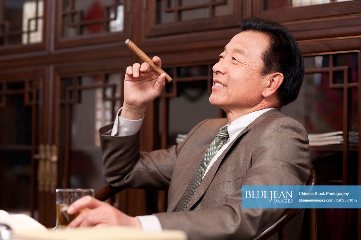 Successful Chinese businessman enjoying cigar