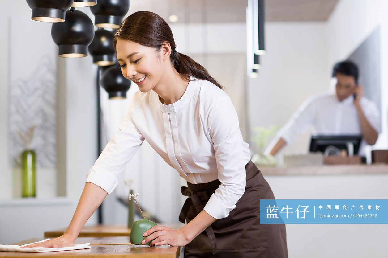 年轻女服务员擦桌子