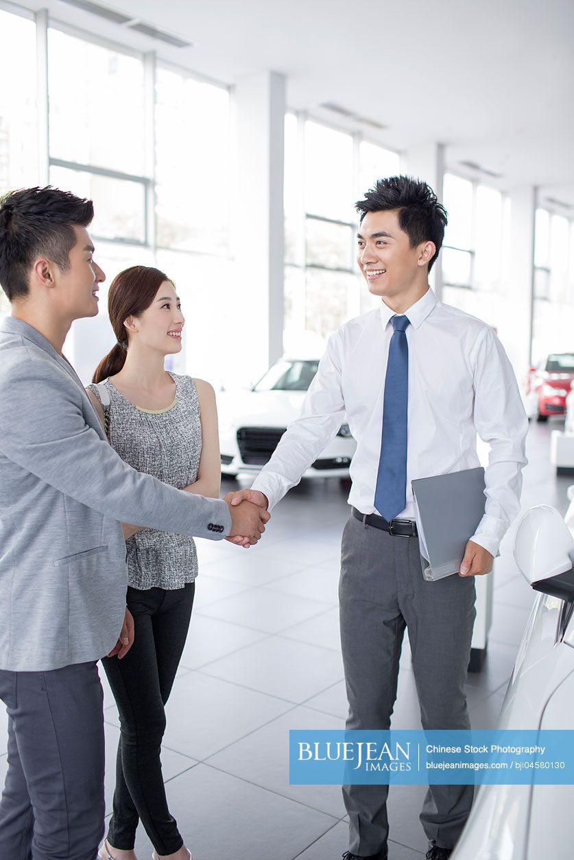 Young Chinese couple buying car in showroom