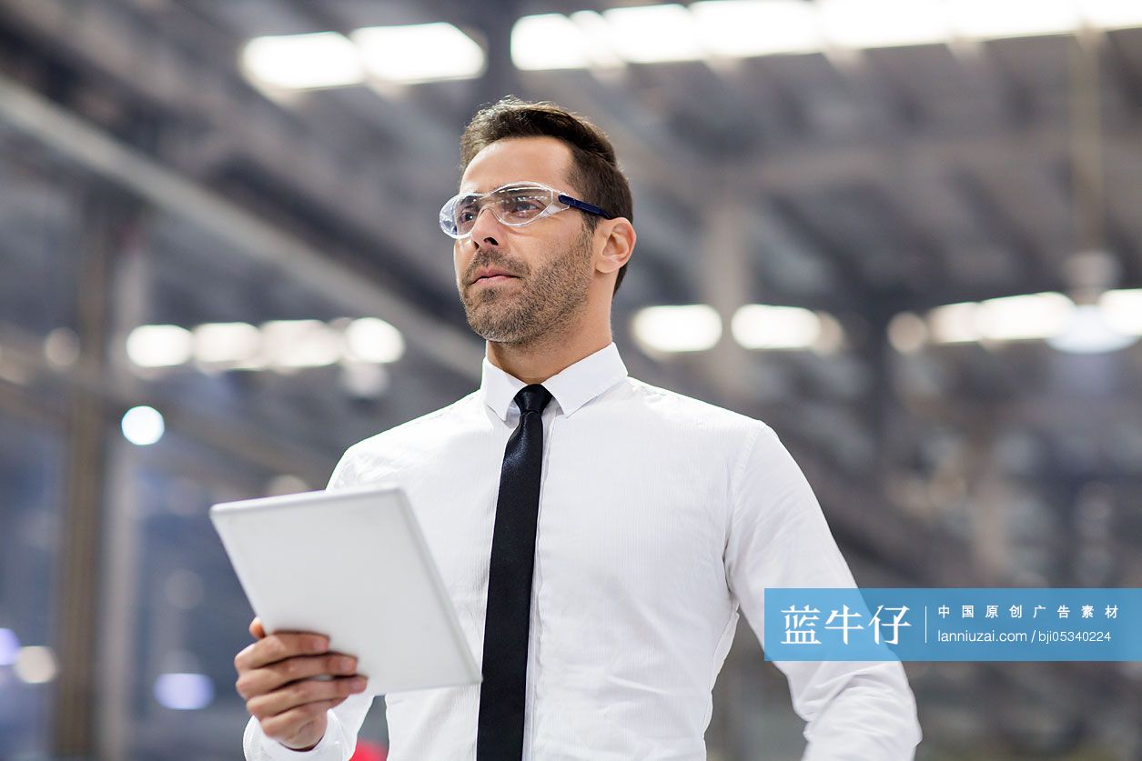 商务男士拿着平板电脑在工厂工作