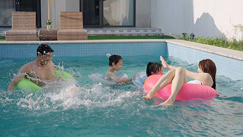 Happy family swimming and playing in the sparkling pool