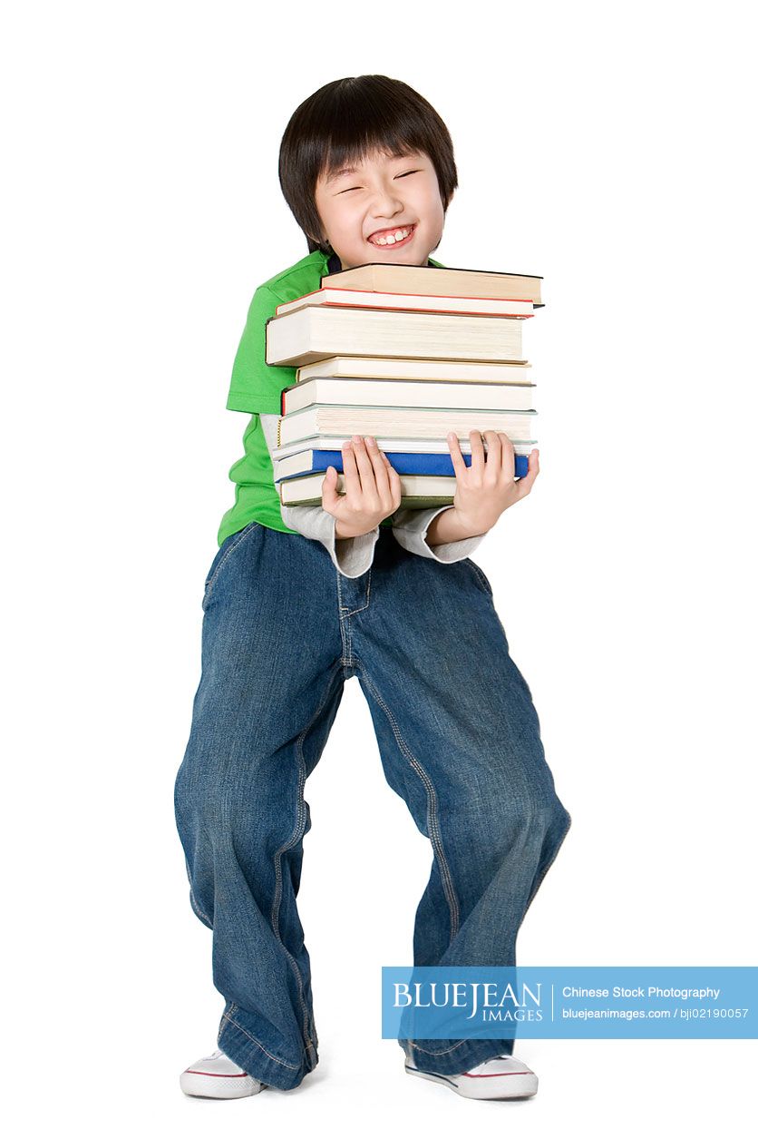 Young Chinese boy carrying a large stack of books