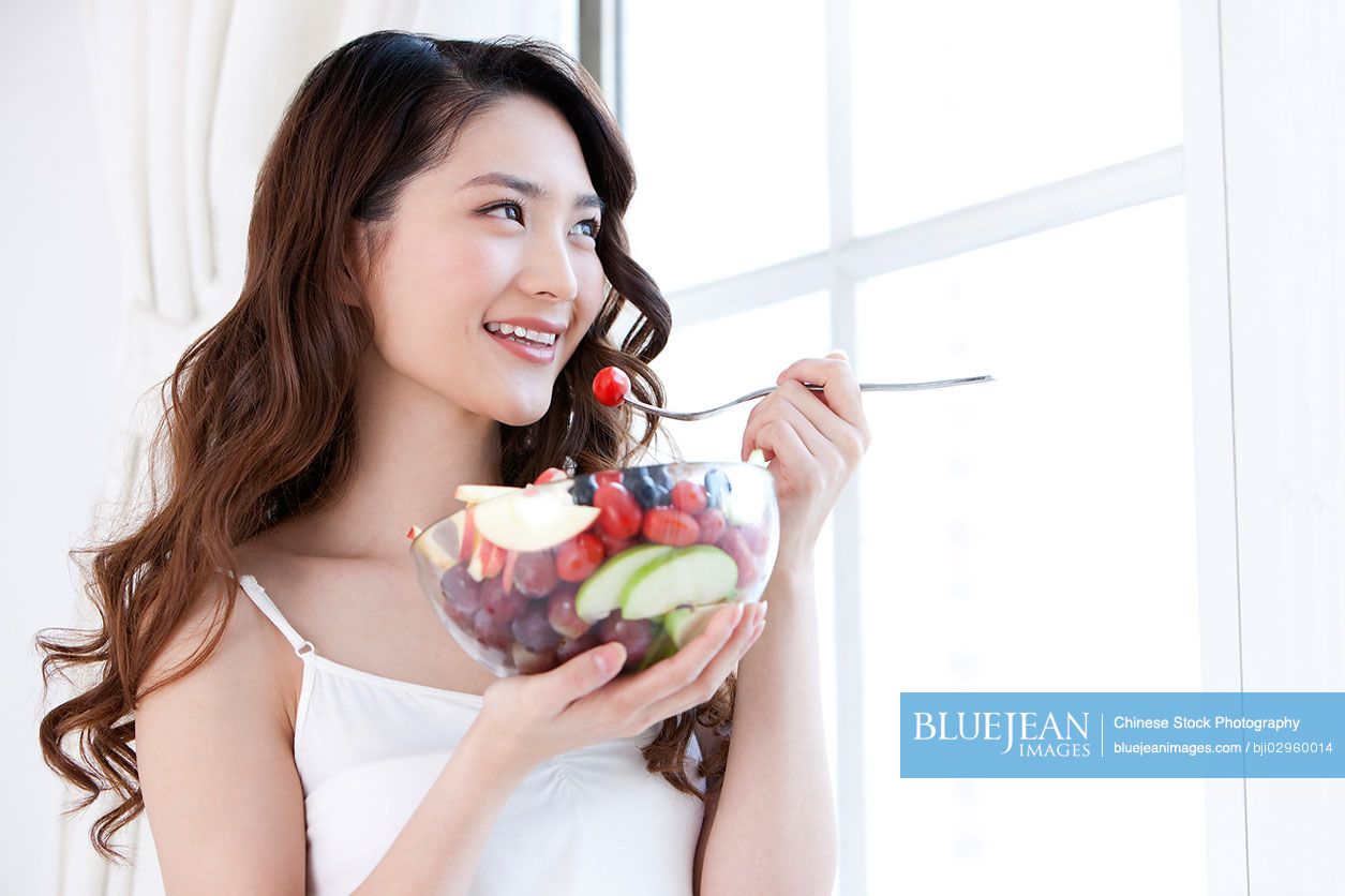 Young Chinese woman eating fruit salad