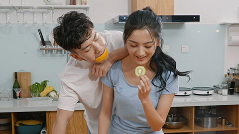 Happy young Chinese couple kissing in kitchen,4K