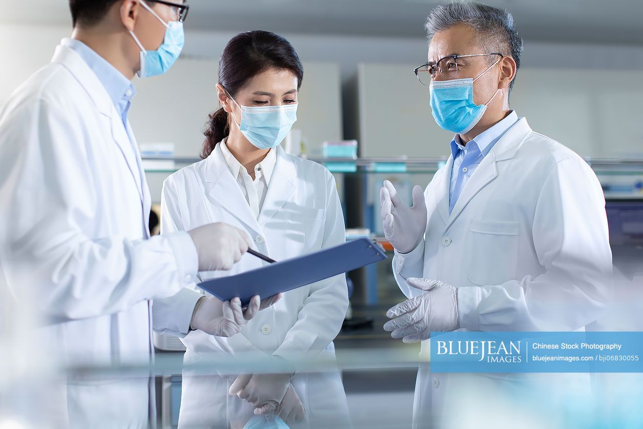 Three Chinese researchers discussing in laboratory