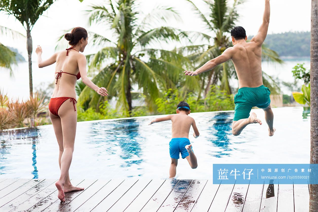 快乐的年轻家庭跳入泳池