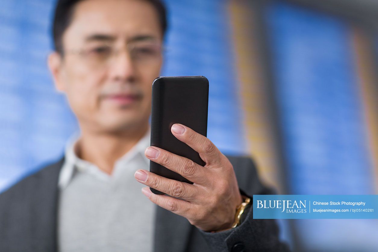 Chinese businessman using smart phone in airport