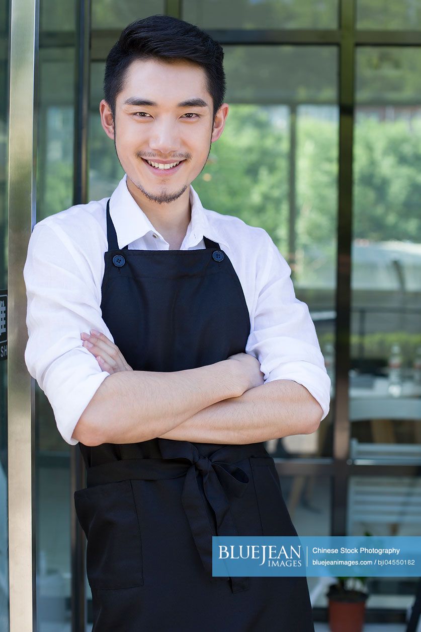 Chinese shopkeeper standing in doorway of coffee shop