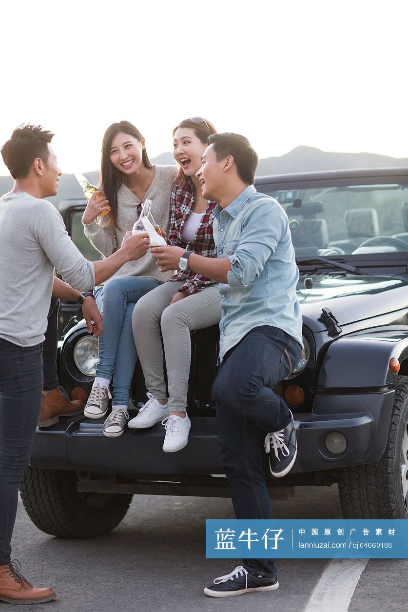 年轻人坐在吉普车上喝啤酒