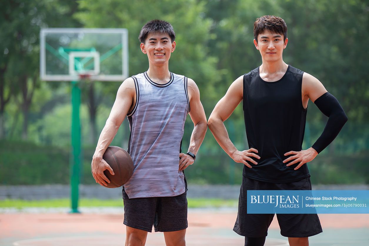 Happy young Chinese men playing basketball outdoors