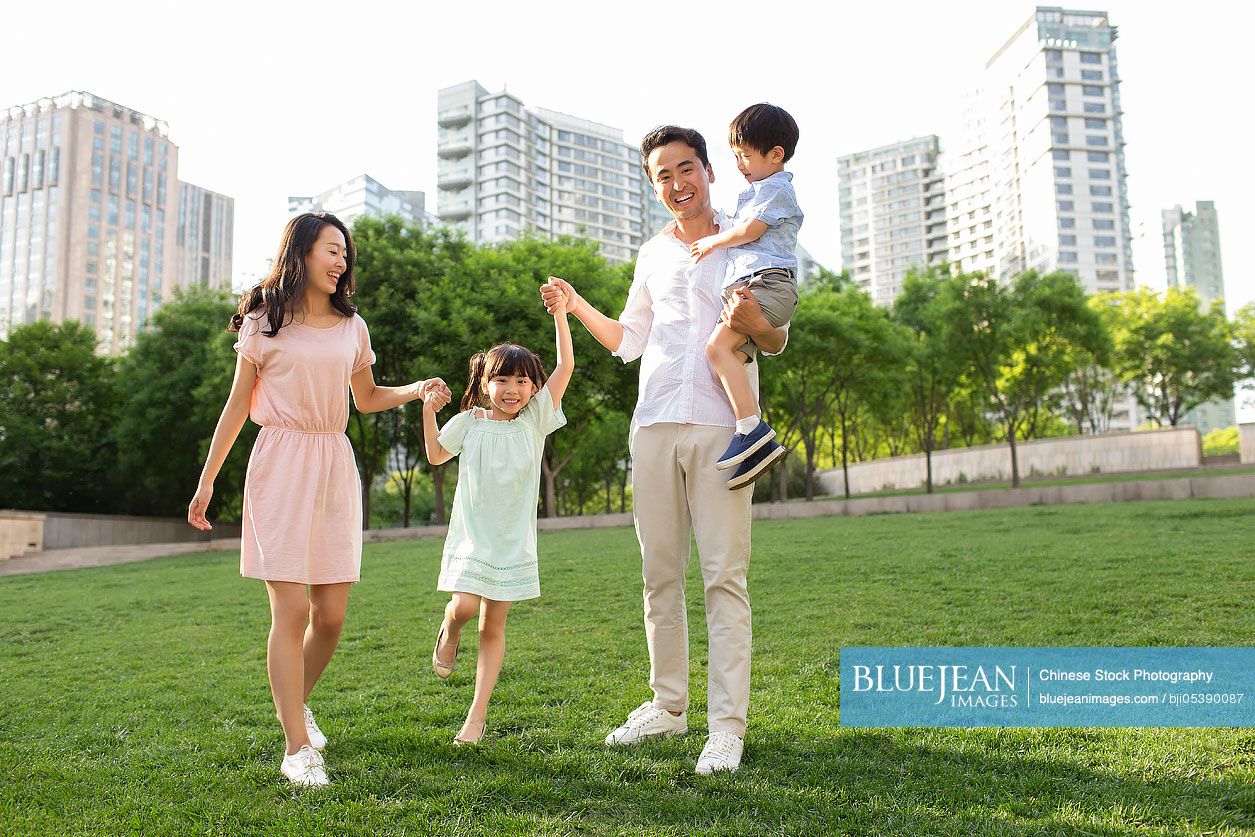 Happy young Chinese family playing in park