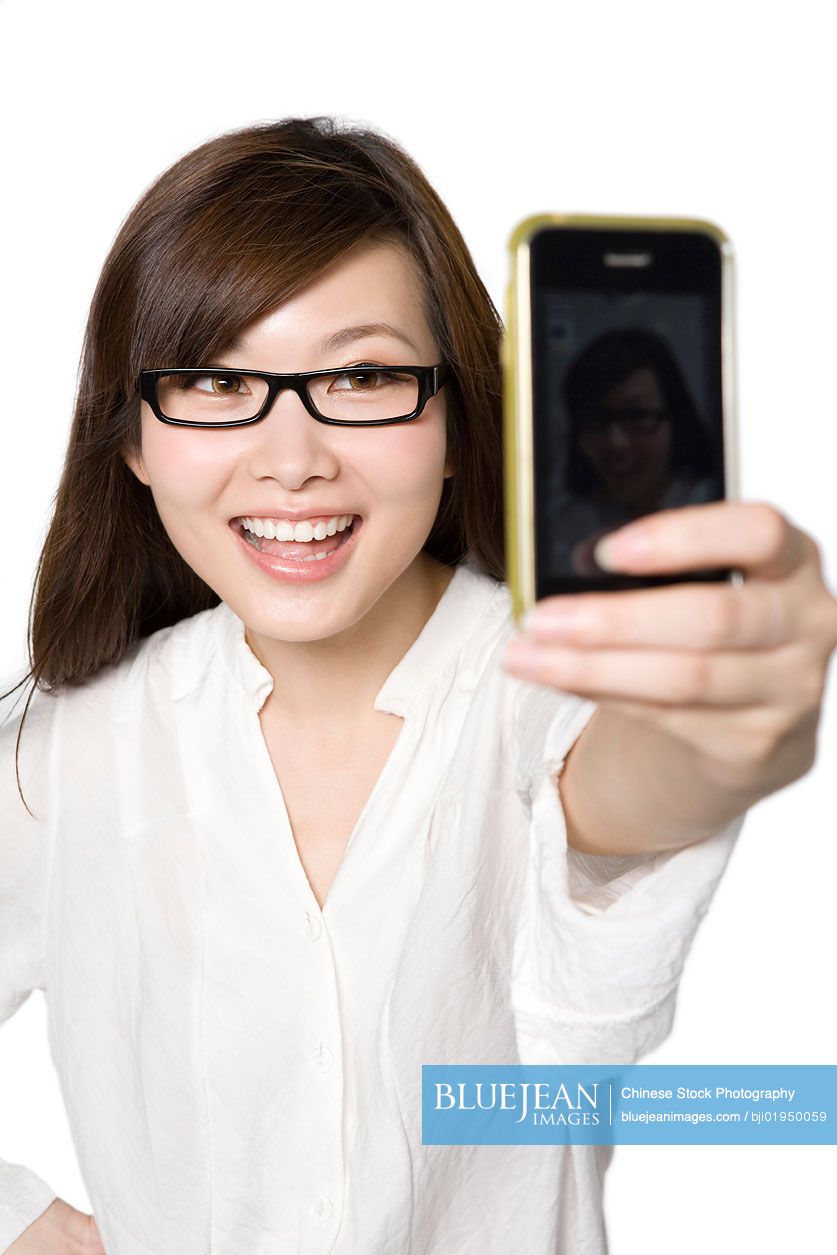 Portrait of young Chinese woman taking a photograph of herself