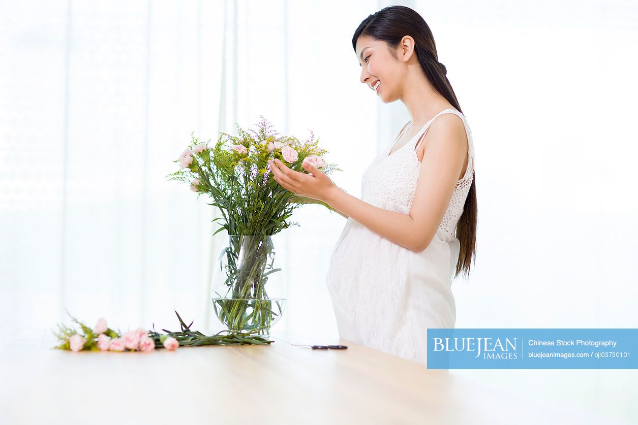 Young pregnant Chinese woman arranging flowers