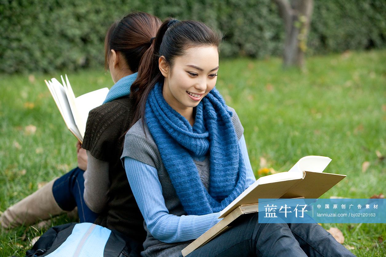 青年女子坐在草地上看书