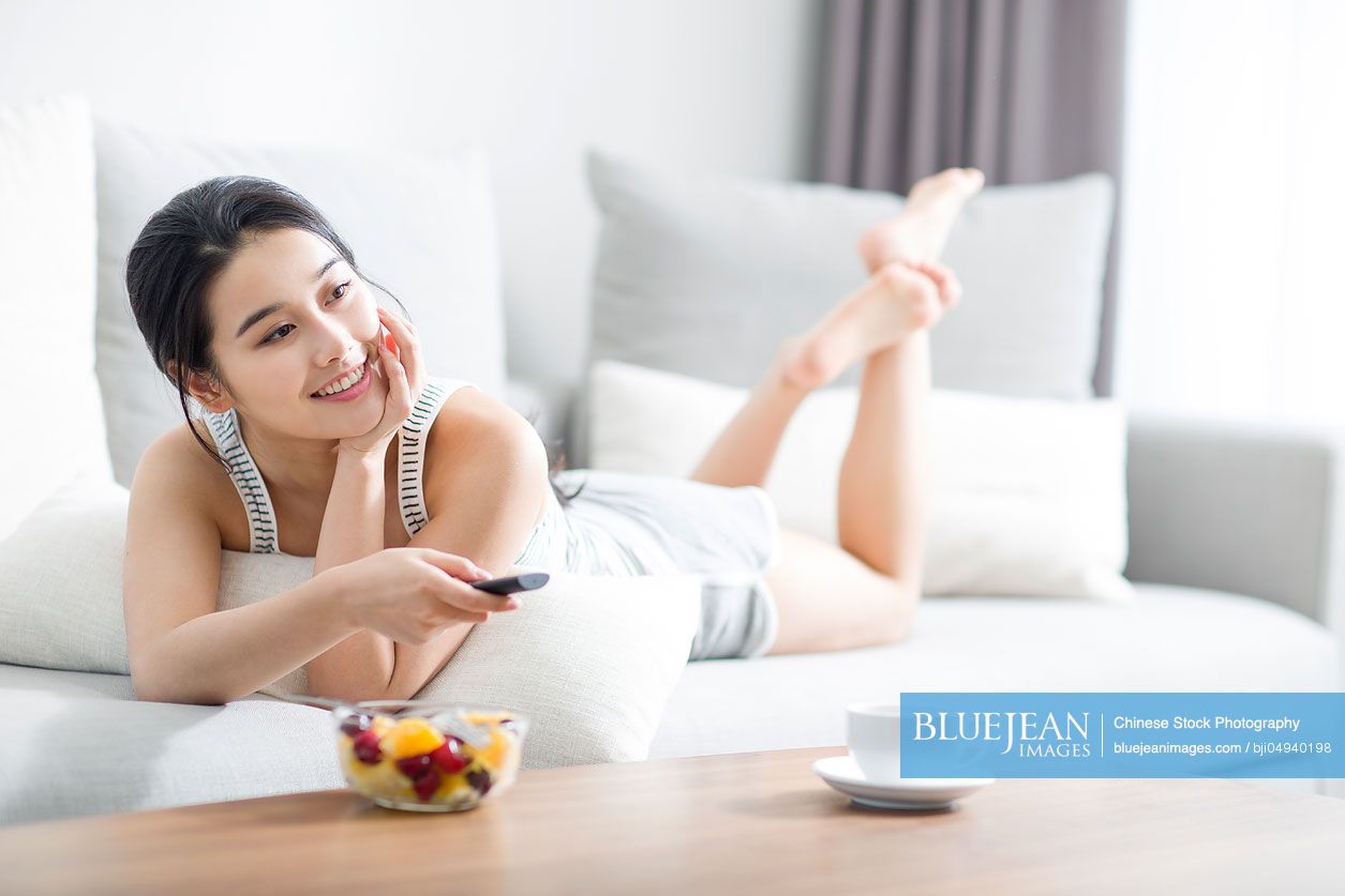 Young Chinese woman watching TV at home