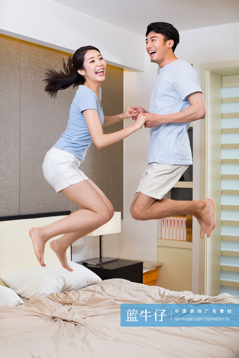 年轻夫妇在床上跳跃