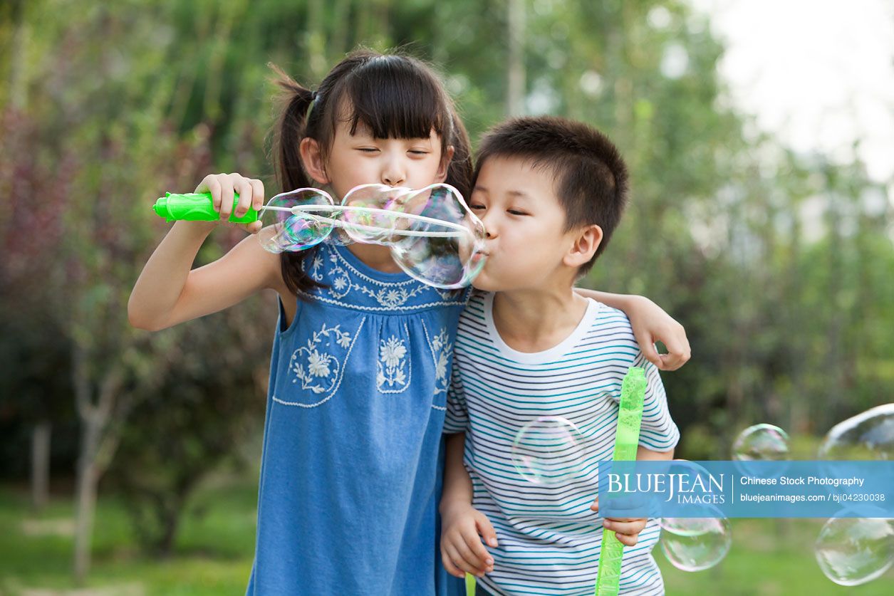 Two Chinese children blowing bubbles