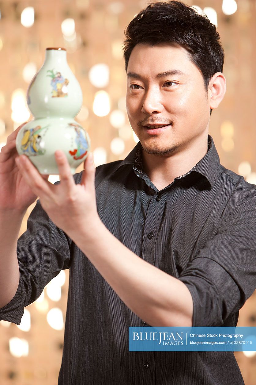 Chinese man admiring antique Chinese vase
