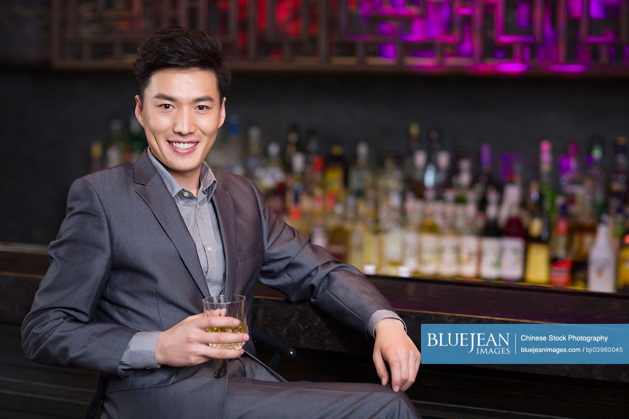 Young Chinese man having a drink at bar