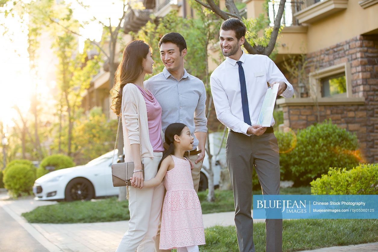 Happy young Chinese family and real estate agent