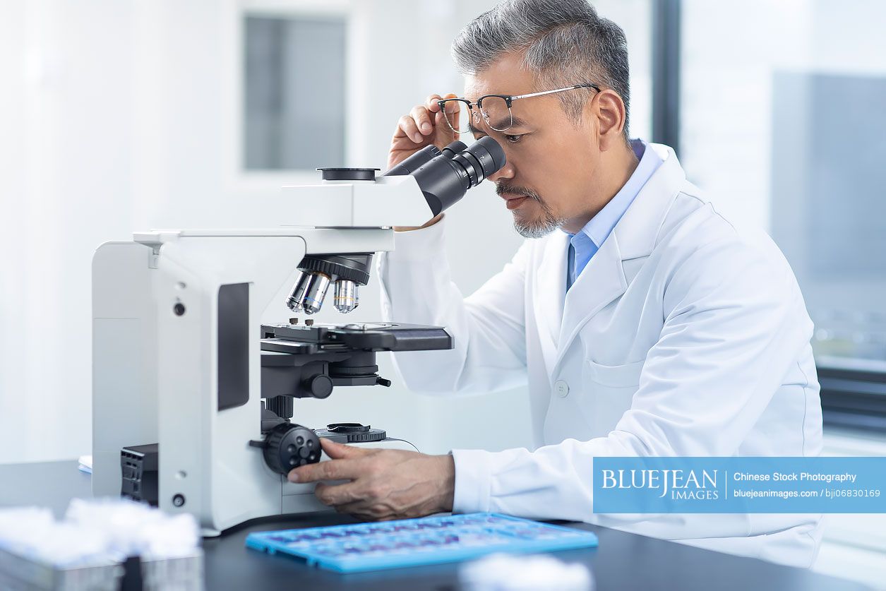 Chinese scientist looking through a microscope