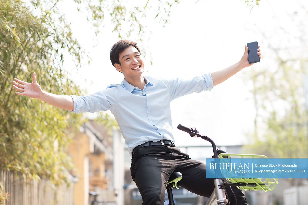 Young Chinese man riding a share bike