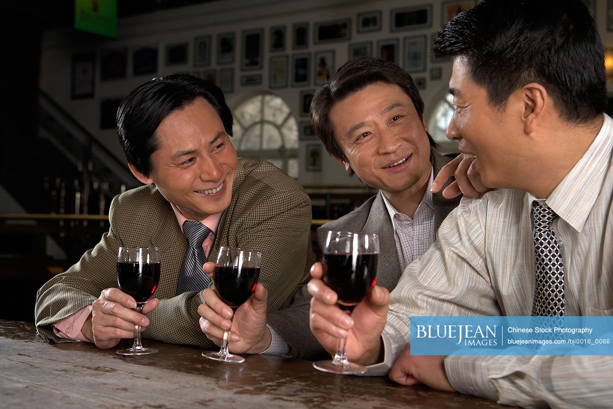 Happy Chinese businessmen drinking at bar