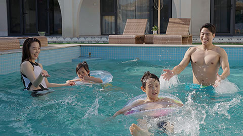Happy family swimming and playing in the sparkling pool
