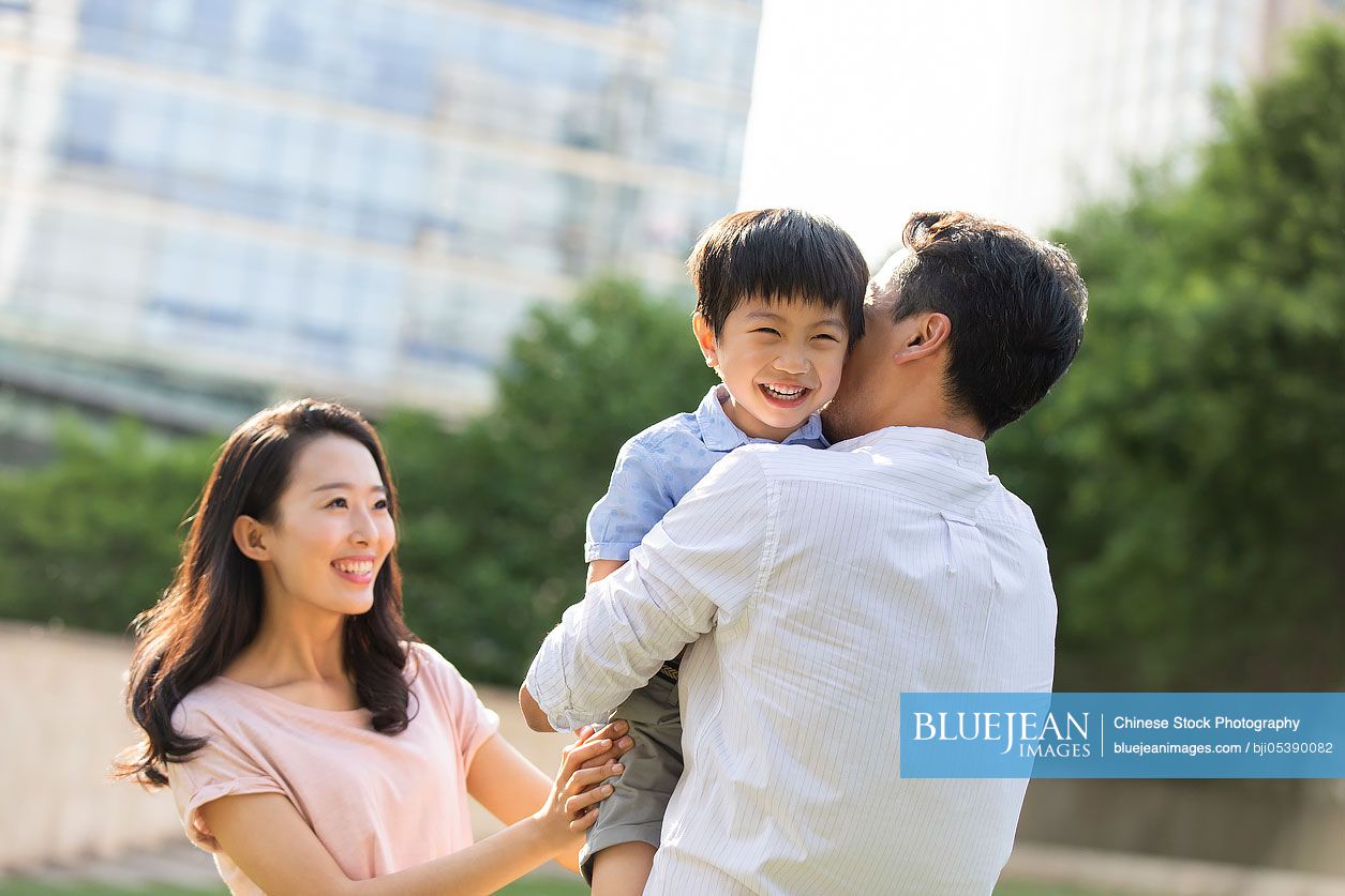 Happy young Chinese family playing in park