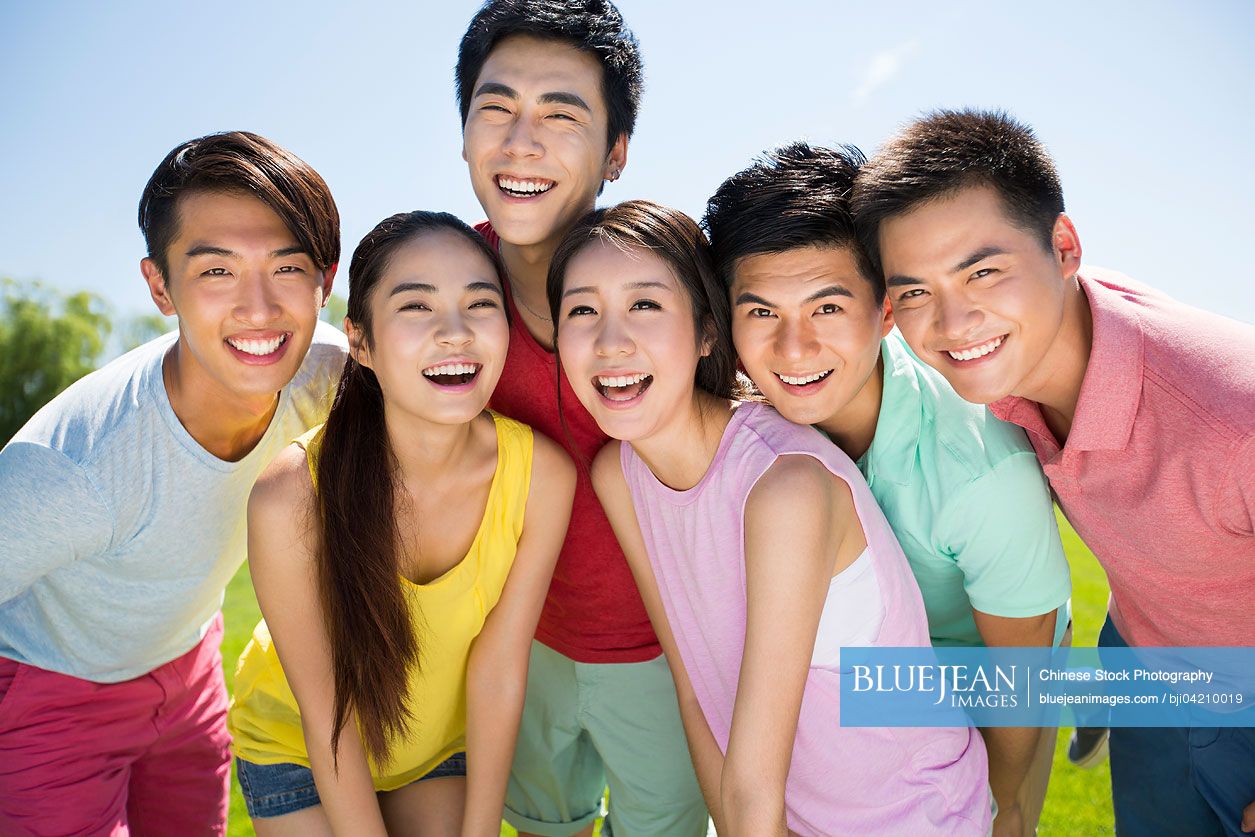 Group photo of cheerful young Chinese adults standing on grass