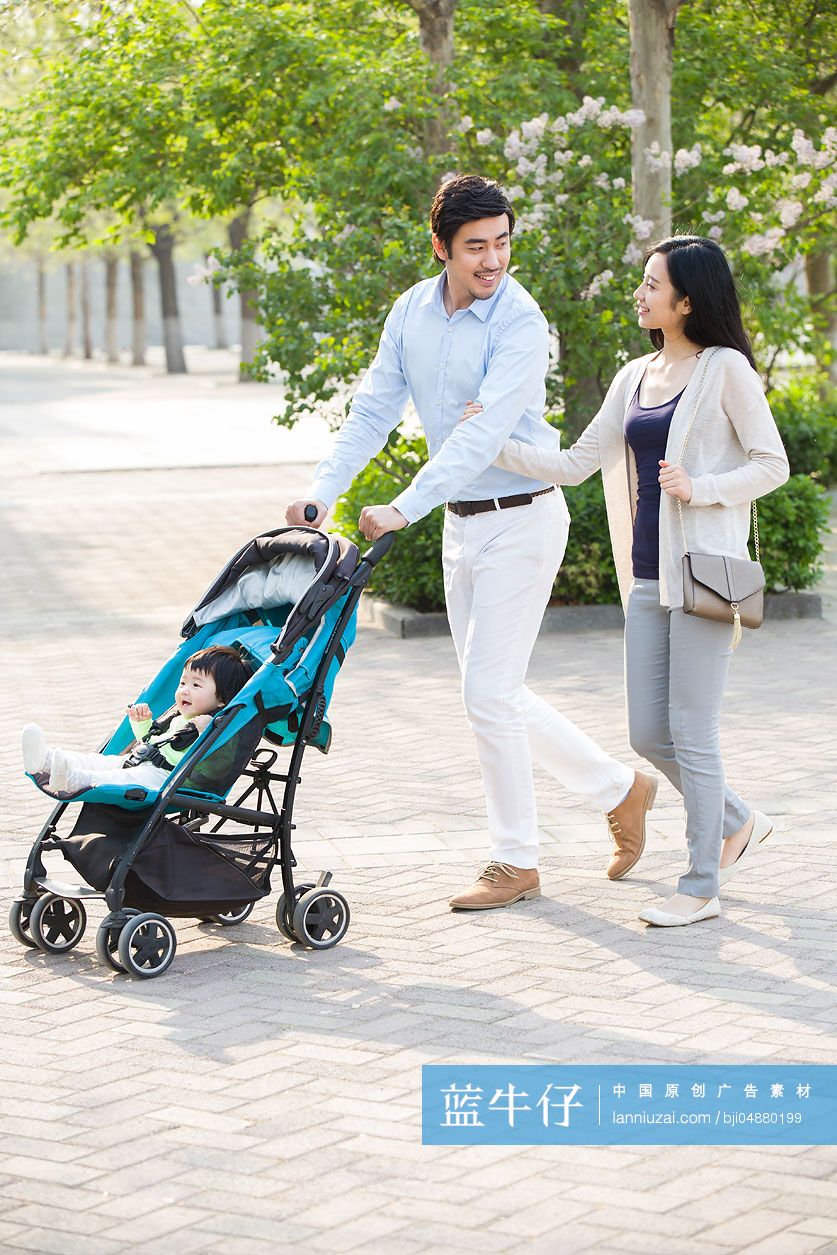 年轻夫妻推着婴儿车散步