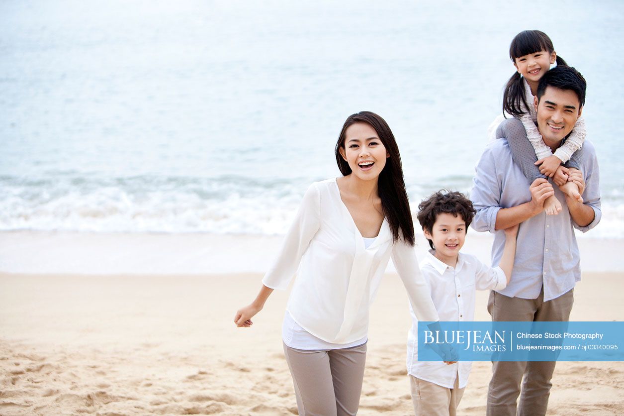 Happy young Chinese family having a good time on the beach of Repulse Bay, Hong Kong