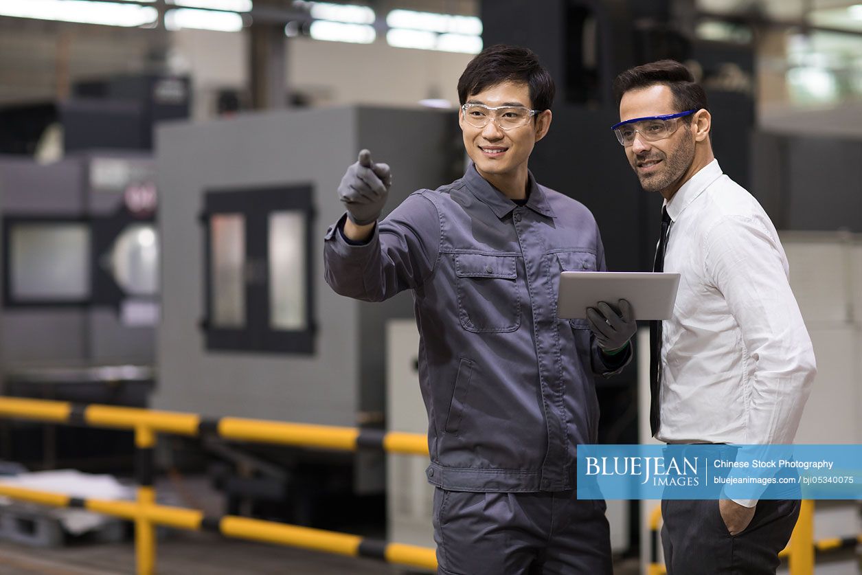 Businessman and engineer talking in the factory