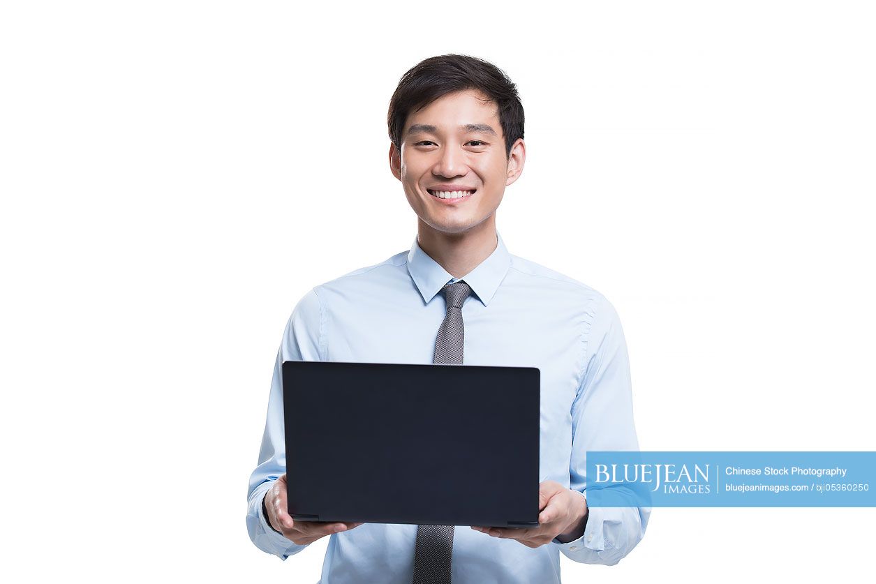 Confident young Chinese businessman holding a laptop