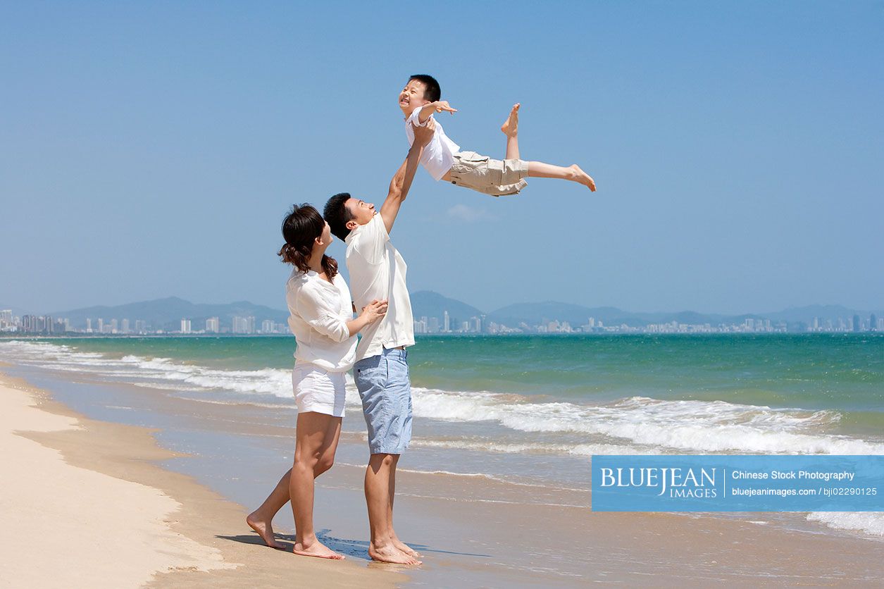 Young Chinese family playing at the beach