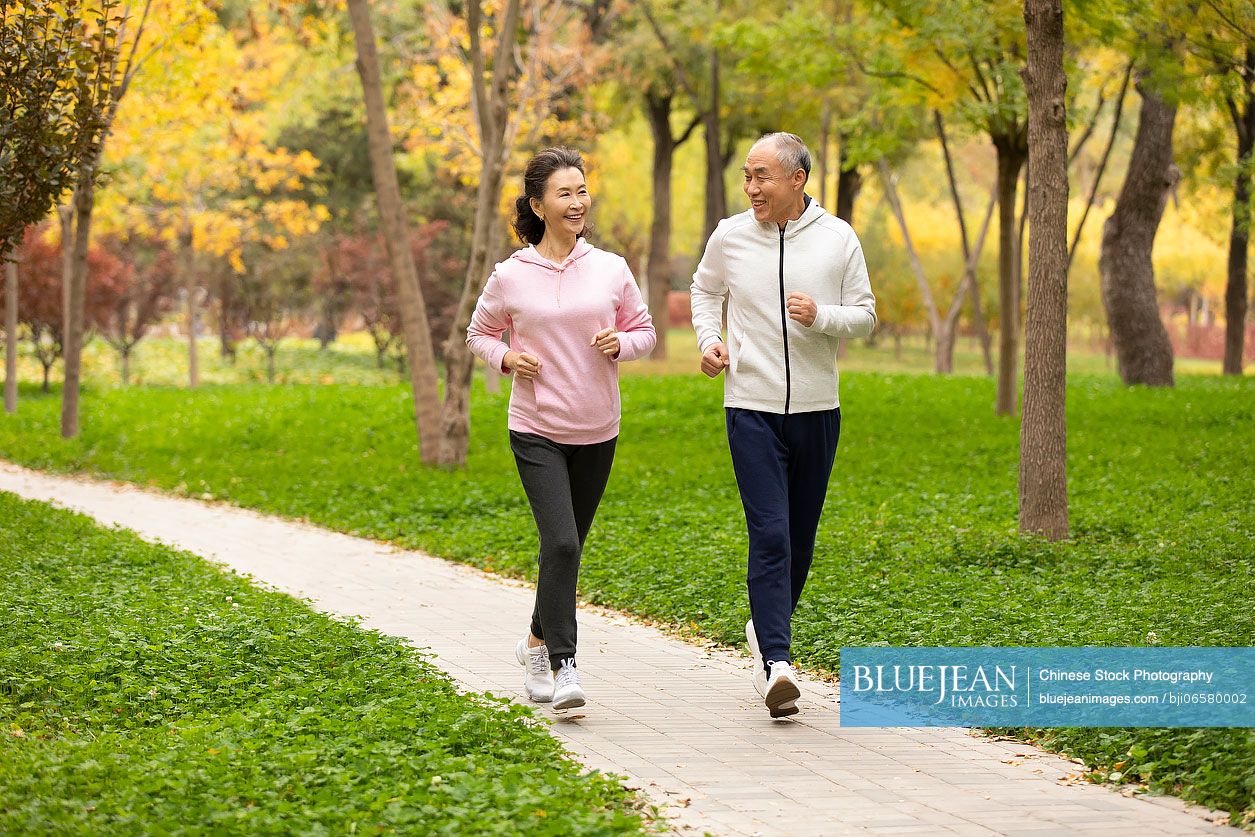 Happy senior Chinese couple running in the park