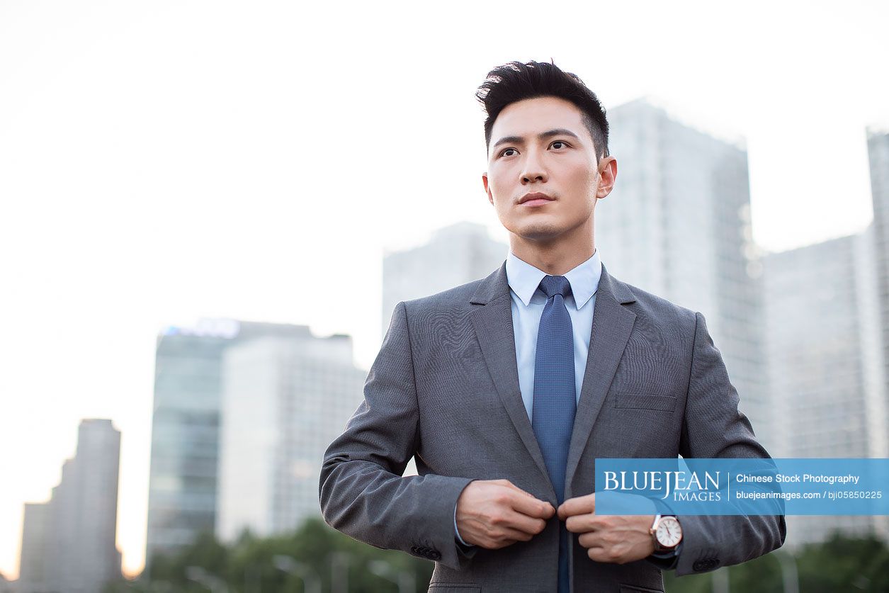 Young Chinese businessman buttoning