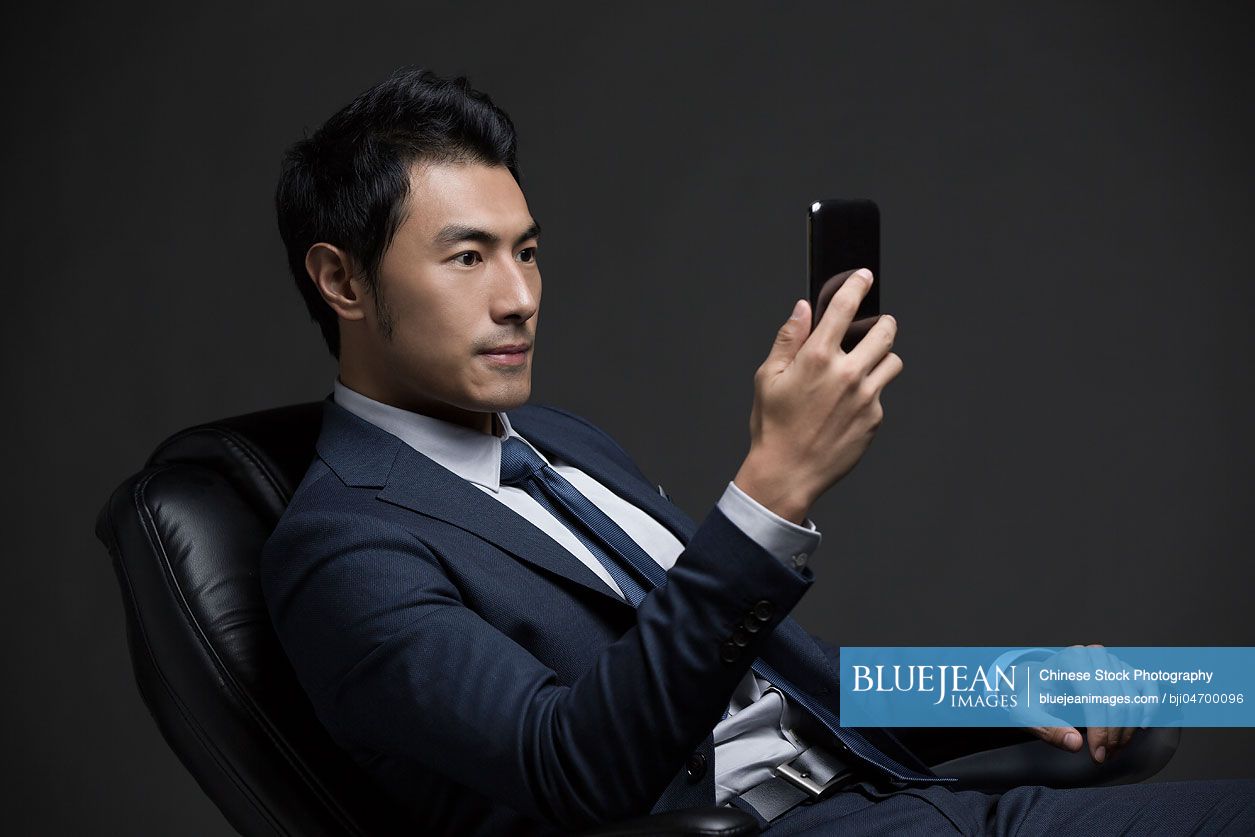 Confident Chinese businessman using smart phone