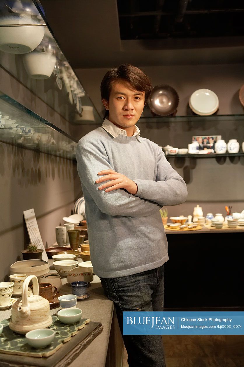 Chinese Young Man Standing Near Objects In Shop