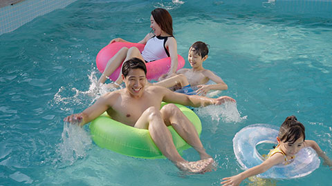 Happy family swimming and playing in the sparkling pool