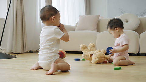 Two twin babies playing with building blocks on the floor