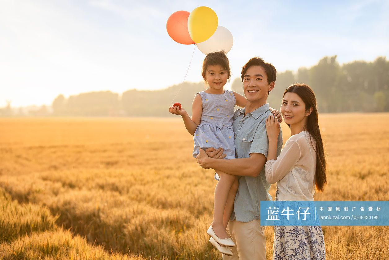 快乐的年轻家庭在麦田里玩耍