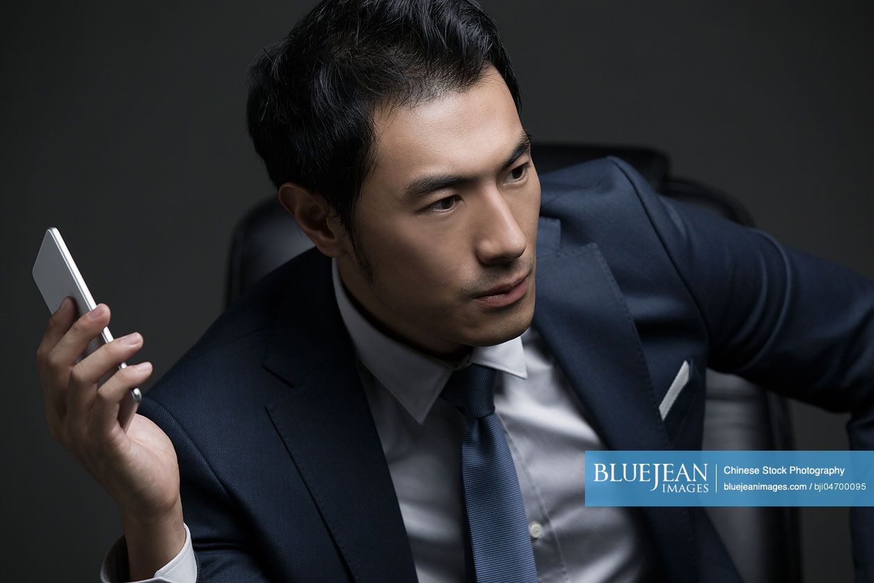 Confident Chinese businessman holding a smart phone