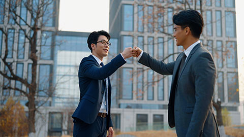 Confident Chinese business people holding hands outdoors