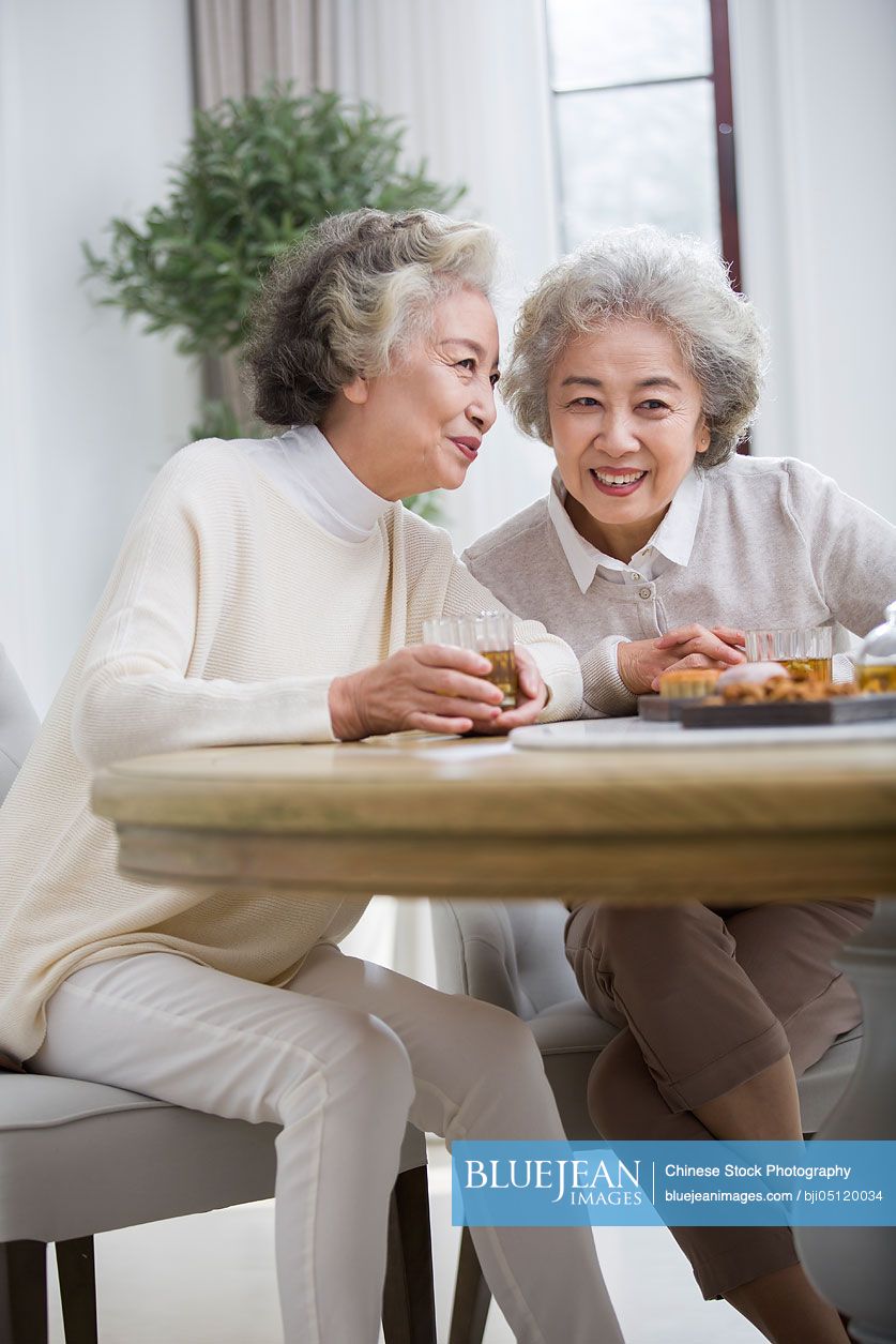 Happy senior Chinese women talking and drinking tea